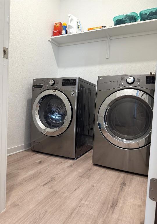 laundry room featuring baseboards, laundry area, washer and clothes dryer, and light wood-style flooring