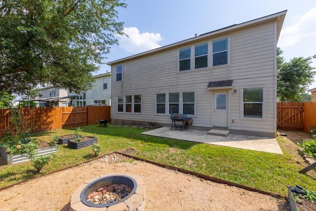 rear view of property featuring a garden, a fire pit, a fenced backyard, a patio area, and a yard