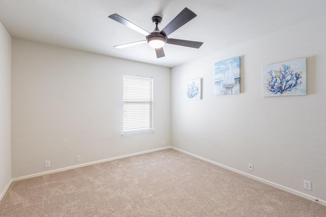 carpeted spare room featuring baseboards and ceiling fan