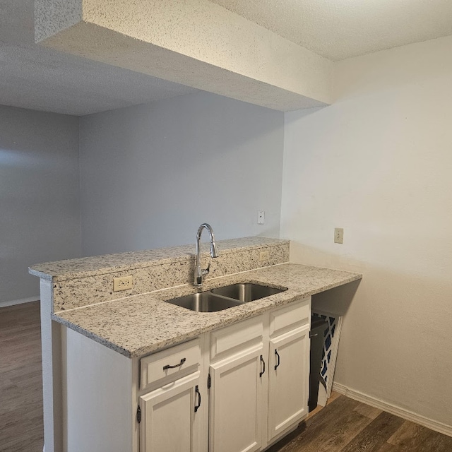 3012 Whisper Oaks Ln Unit I, Georgetown, TX 78628 - kitchen with a sink, a peninsula, dark wood-style floors, baseboards, and white cabinets