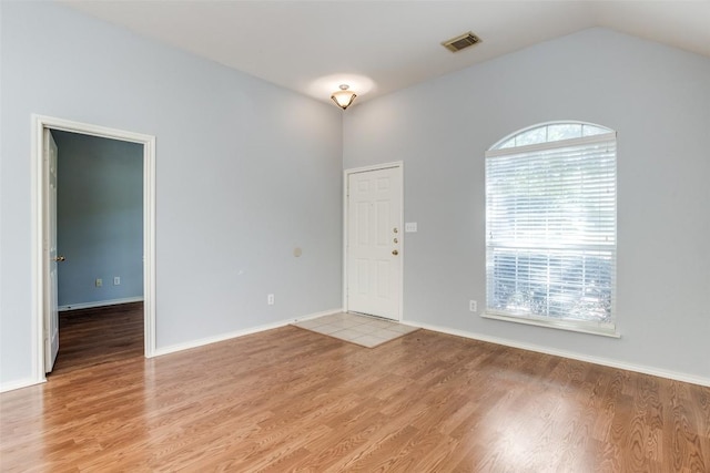 interior space featuring visible vents, baseboards, lofted ceiling, and light wood-type flooring