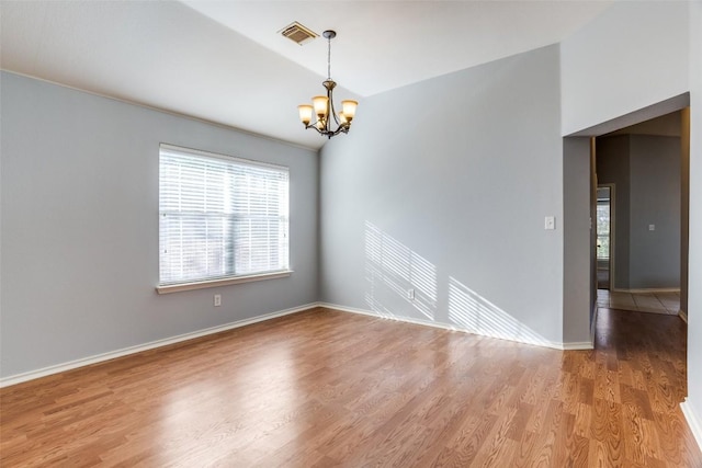 spare room with light wood-style floors, baseboards, a notable chandelier, and visible vents