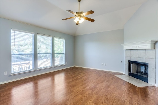 unfurnished living room featuring a ceiling fan, baseboards, wood finished floors, lofted ceiling, and a tile fireplace