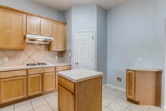 kitchen featuring tasteful backsplash, light tile patterned floors, light countertops, under cabinet range hood, and white gas stovetop