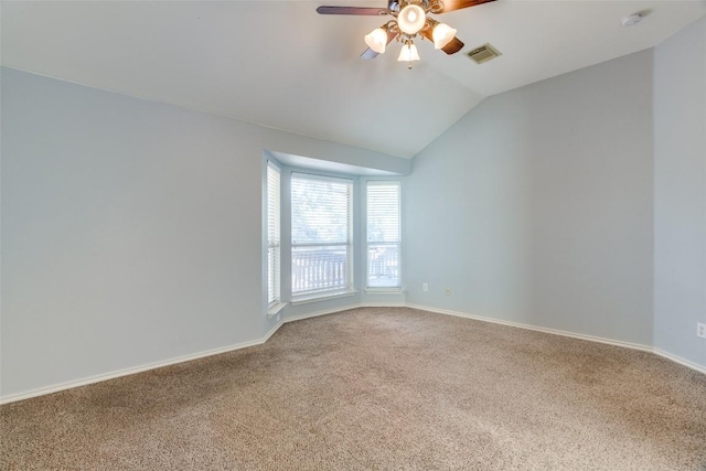 spare room featuring carpet, a ceiling fan, lofted ceiling, and visible vents