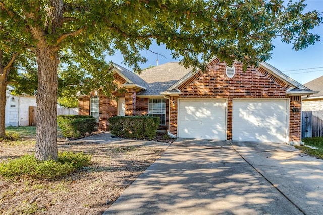 traditional-style home featuring driveway, a garage, brick siding, fence, and a shingled roof