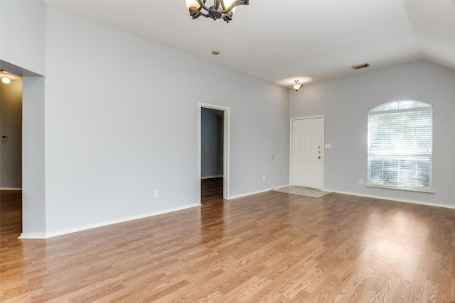 unfurnished living room with visible vents, vaulted ceiling, light wood finished floors, and a notable chandelier