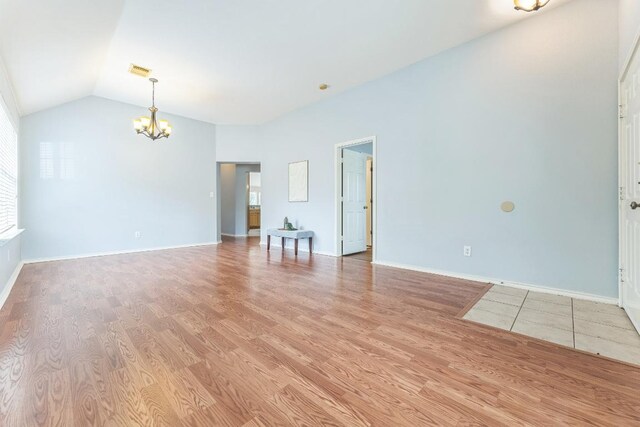 7418 W Magic Mountain Ln, Round Rock, TX 78681 - unfurnished living room featuring baseboards, an inviting chandelier, visible vents, vaulted ceiling, and light wood-style floors