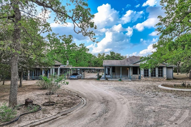 view of front of home with a porch, a detached carport, and dirt driveway