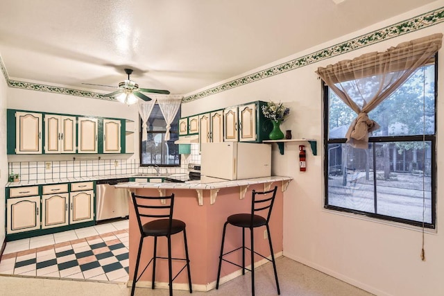 kitchen with a peninsula, a kitchen bar, under cabinet range hood, a ceiling fan, and stainless steel appliances