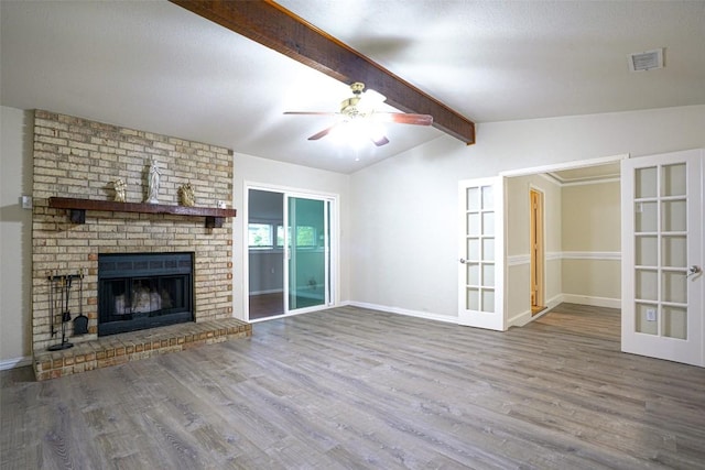 unfurnished living room with a ceiling fan, french doors, visible vents, wood finished floors, and lofted ceiling with beams