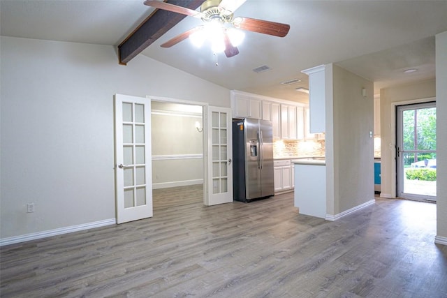 kitchen with stainless steel refrigerator with ice dispenser, white cabinets, french doors, and tasteful backsplash