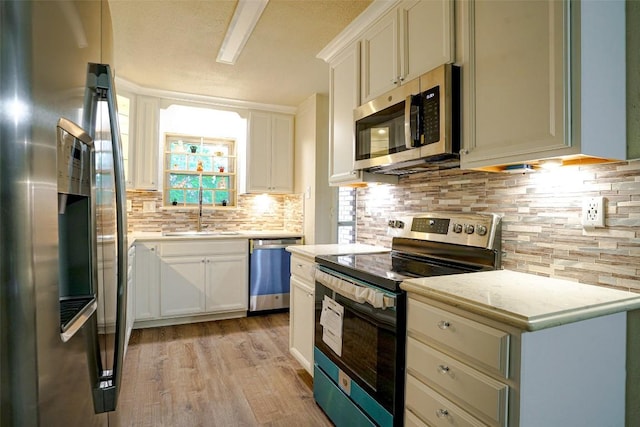 kitchen featuring light countertops, a sink, appliances with stainless steel finishes, and backsplash