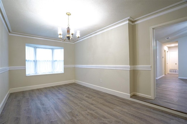 empty room featuring crown molding, visible vents, wood finished floors, baseboards, and a notable chandelier