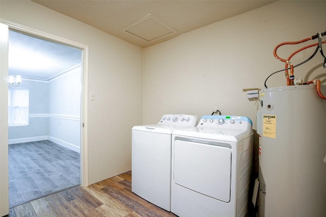 clothes washing area with water heater, laundry area, light wood finished floors, and washer and clothes dryer