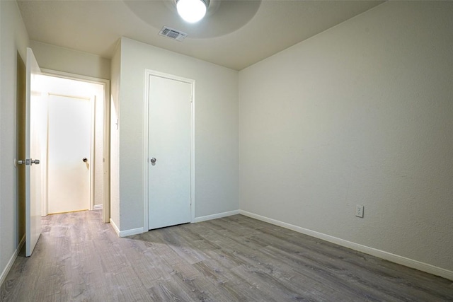 unfurnished bedroom with baseboards, a ceiling fan, wood finished floors, and visible vents