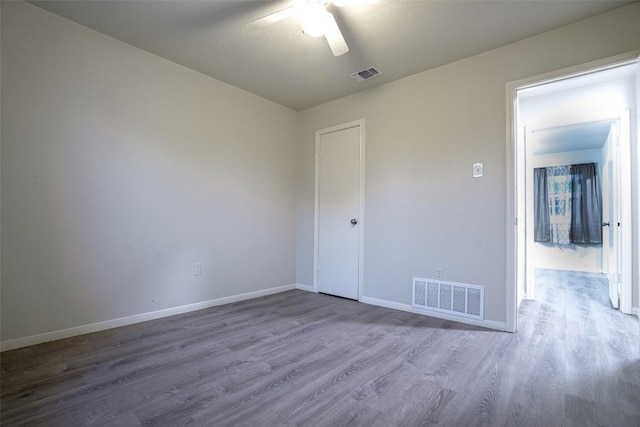 empty room featuring a ceiling fan, baseboards, visible vents, and wood finished floors