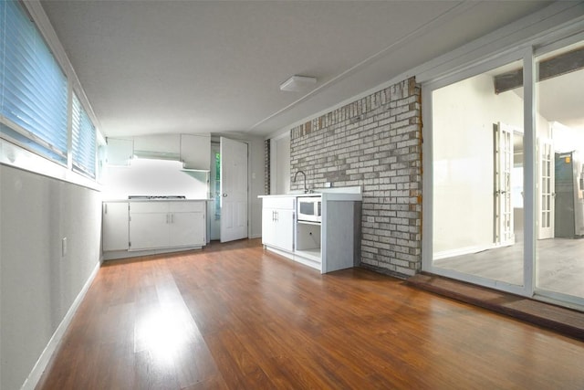 unfurnished room with baseboards, a sink, and wood finished floors