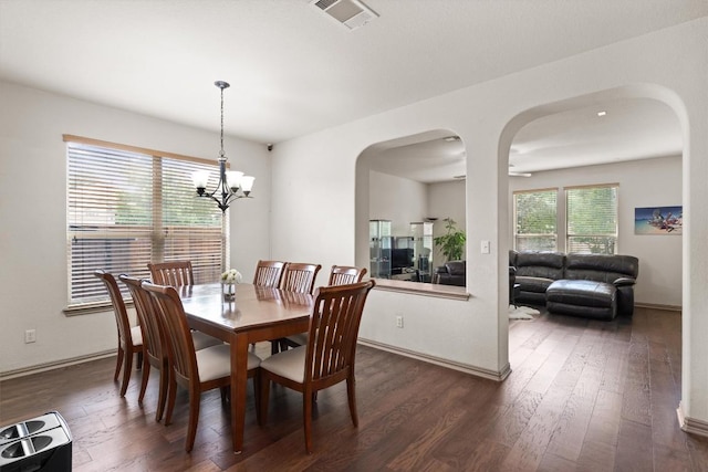 dining area with arched walkways, visible vents, and dark wood-style floors