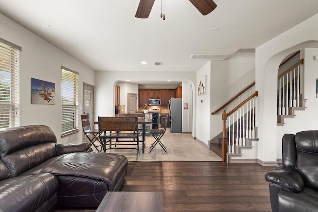 living room featuring a ceiling fan, arched walkways, stairs, recessed lighting, and light wood-style flooring