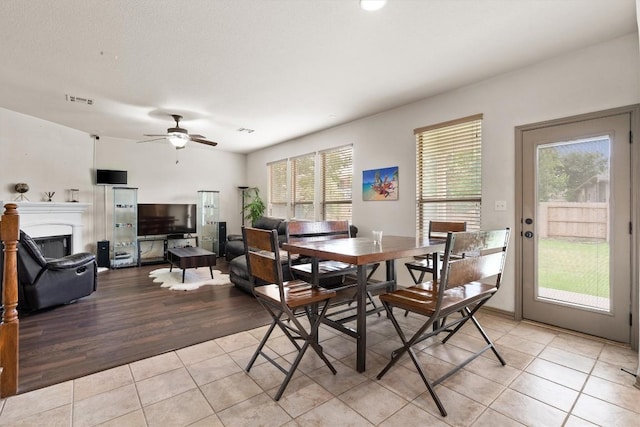 dining area featuring visible vents, a ceiling fan, light tile patterned flooring, and a fireplace