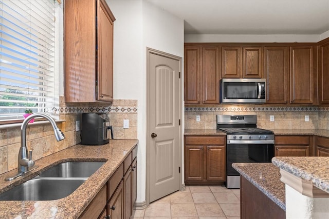 kitchen featuring a sink, decorative backsplash, light stone countertops, and stainless steel appliances