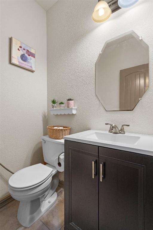 bathroom featuring toilet, a textured wall, and vanity