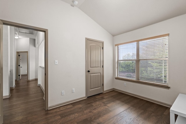 unfurnished bedroom featuring baseboards, lofted ceiling, attic access, and dark wood-type flooring