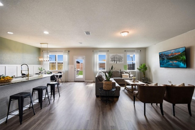 living room featuring dark wood-type flooring, recessed lighting, a textured ceiling, and visible vents
