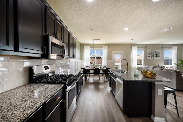 kitchen featuring visible vents, dark wood-style flooring, open floor plan, a sink, and stainless steel appliances