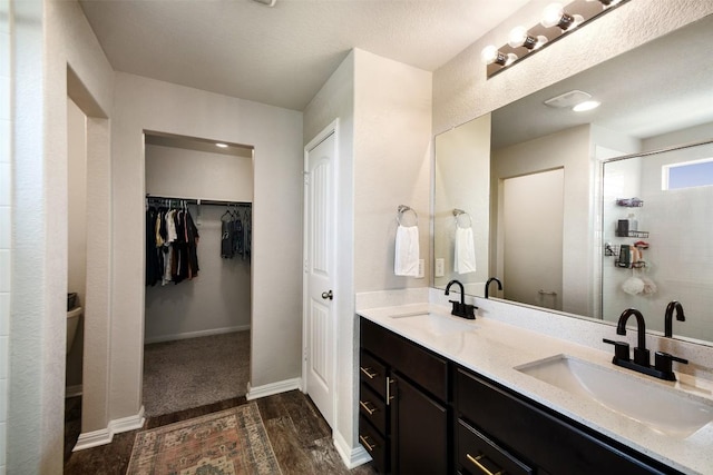 full bath with double vanity, a sink, a stall shower, and wood finished floors