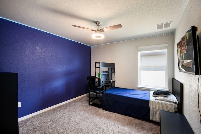 carpeted bedroom featuring baseboards, a ceiling fan, a textured ceiling, and visible vents