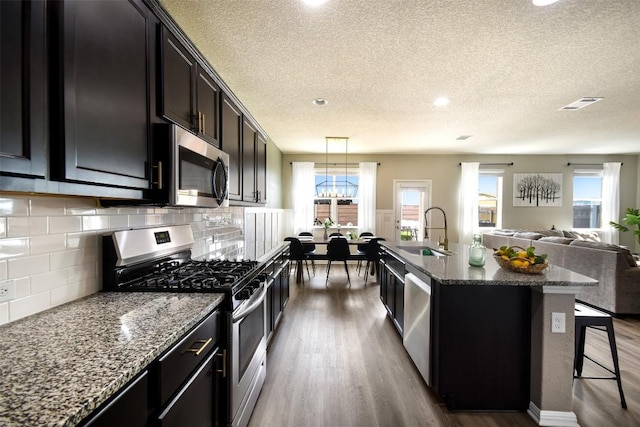 217 Frederick Dr, Georgetown, TX 78626 - kitchen with stainless steel appliances, wood finished floors, a textured ceiling, open floor plan, and tasteful backsplash