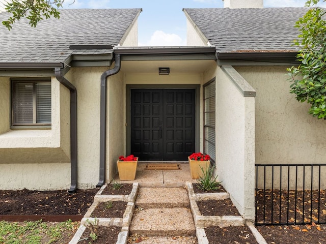 doorway to property featuring roof with shingles and stucco siding
