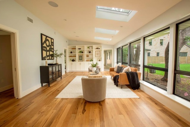 sunroom featuring vaulted ceiling with skylight, baseboards, wood finished floors, and visible vents