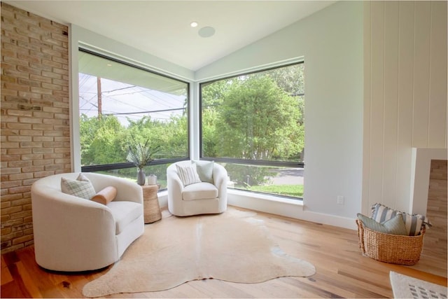 sitting room with a healthy amount of sunlight, wood finished floors, and lofted ceiling