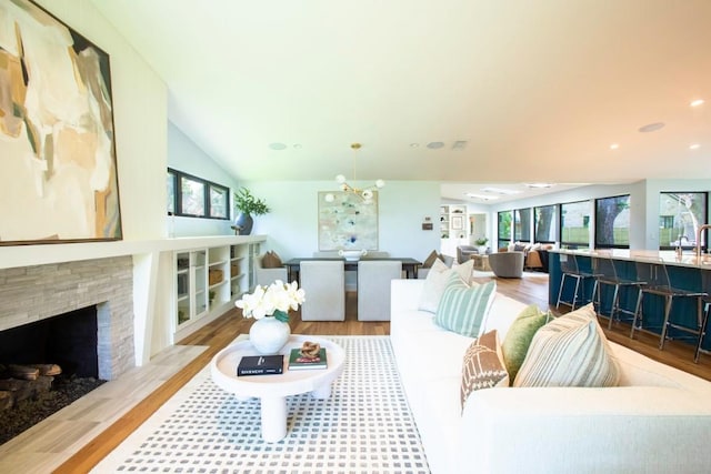 living room featuring a stone fireplace, light wood-style flooring, and lofted ceiling