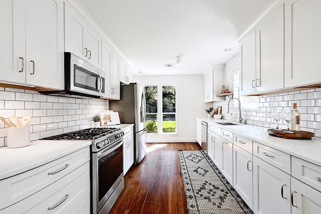 kitchen with a sink, light countertops, stainless steel appliances, and white cabinetry