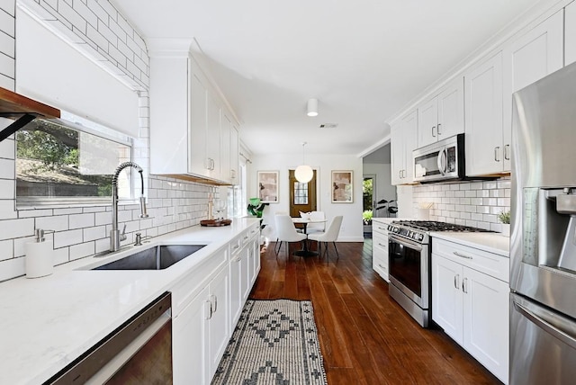 kitchen with light countertops, stainless steel appliances, tasteful backsplash, and a sink