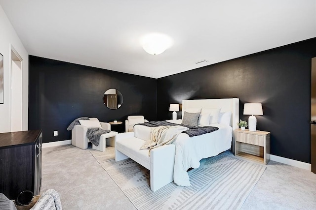 bedroom with light colored carpet, visible vents, baseboards, and an accent wall