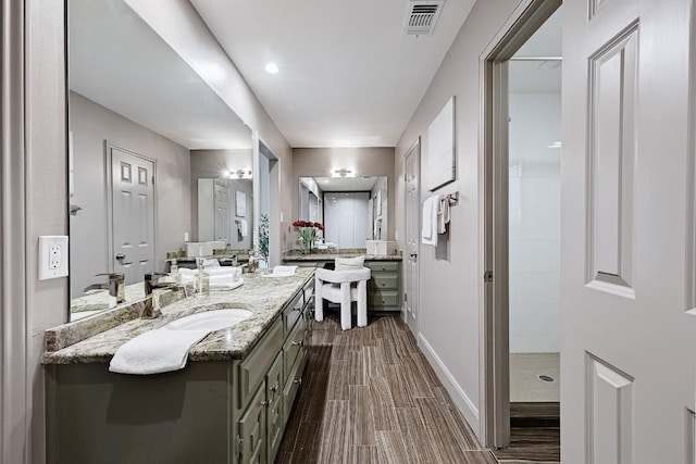 bathroom with visible vents, wood finished floors, vanity, baseboards, and tiled shower