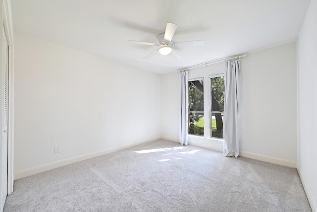 carpeted spare room featuring baseboards and a ceiling fan