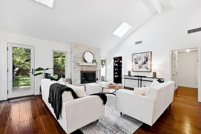 living room featuring a fireplace, a skylight, high vaulted ceiling, and visible vents