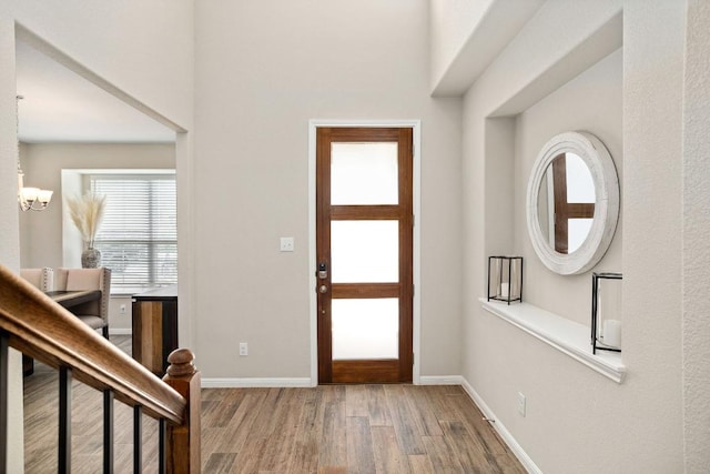entrance foyer featuring an inviting chandelier, baseboards, and wood finished floors