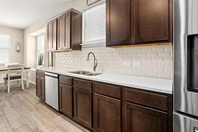 kitchen featuring light countertops, stainless steel appliances, decorative backsplash, and a sink