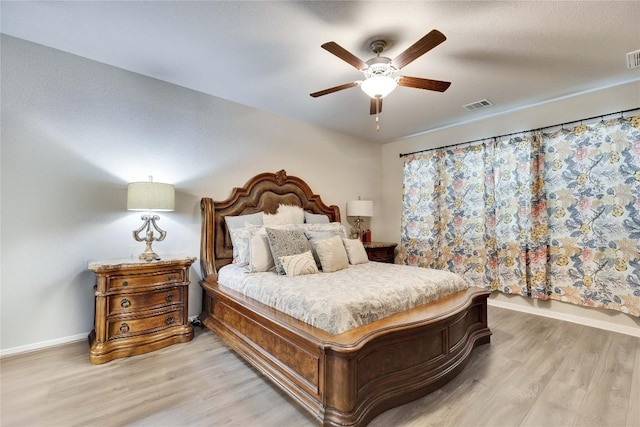 bedroom featuring visible vents, a ceiling fan, baseboards, and light wood finished floors