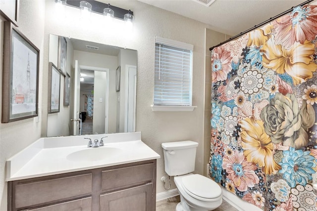 bathroom featuring vanity, a textured wall, toilet, and visible vents