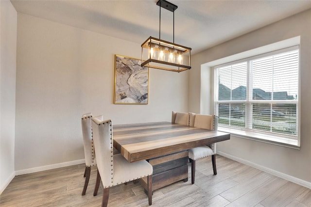 dining space featuring baseboards, light wood-style flooring, and a notable chandelier