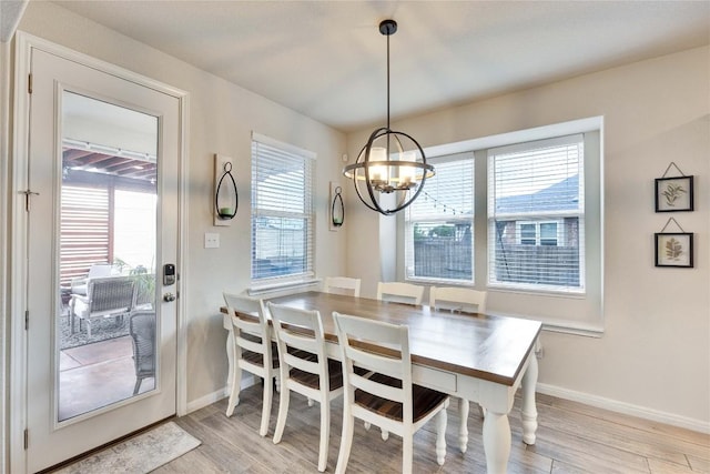 dining room featuring baseboards, light wood finished floors, and a notable chandelier