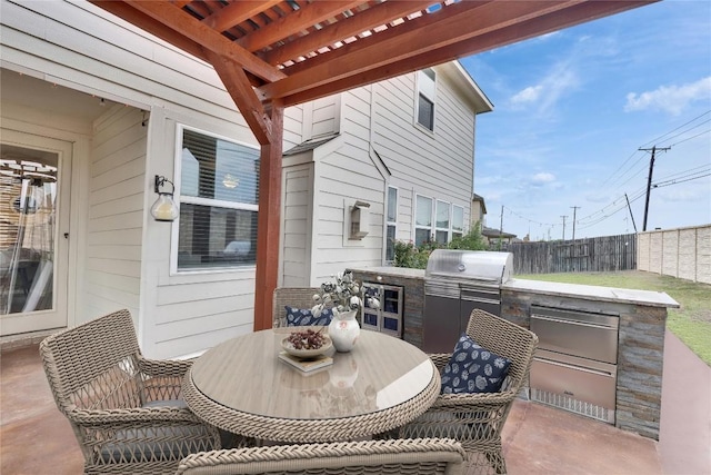 view of patio featuring exterior kitchen, fence, outdoor dining space, and a pergola